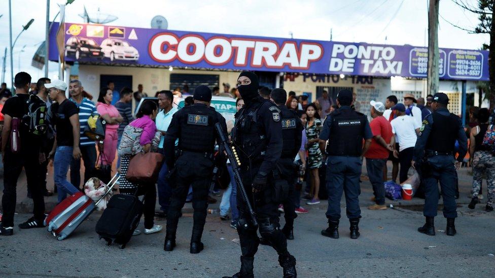 Riot policemen talk with people from Venezuela after checking their passports or identity cards at the Pacaraima border control, Roraima state, Brazil August 19, 2018