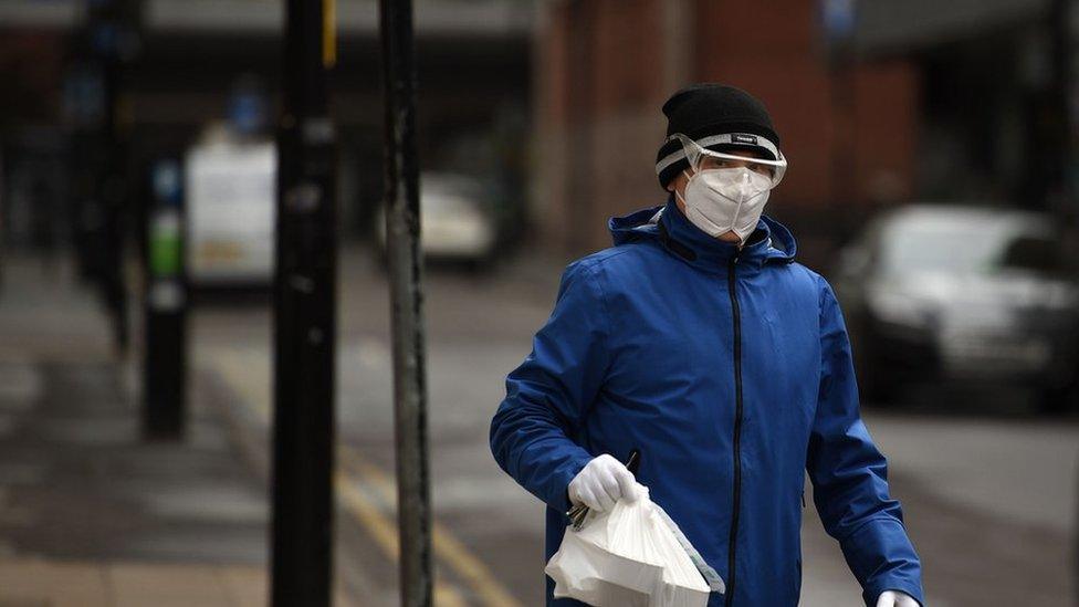 A person with a face mask worn as a precautionary measure against the novel coronavirus COVID-19 walks in Manchester on April 2, 2020, - Prime Minister Boris Johnson said Britain would "massively increase testing" amid a growing wave of criticism on Thursday about his government"s failure to provide widespread coronavirus screening.