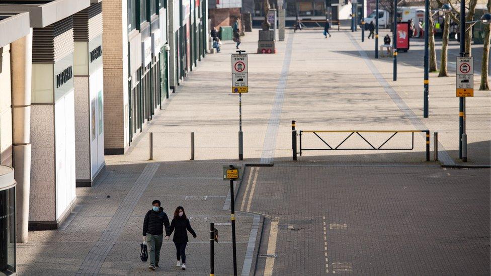 A couple wearing protective equipment walk by the Bullring in Birmingham, the day after Prime Minister Boris Johnson put the UK in lockdown to help curb the spread of the coronavirus