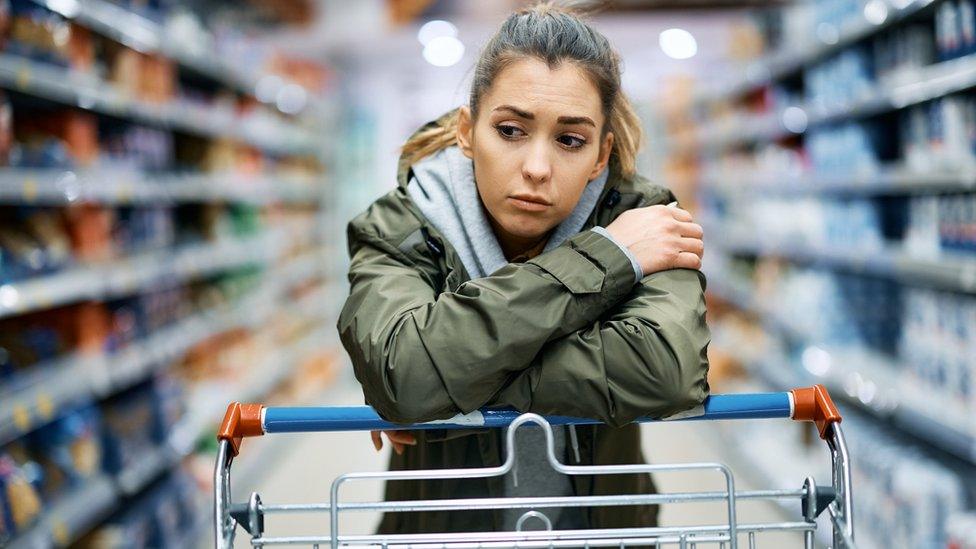 Woman leaning on a shopping trolley in a supermarket