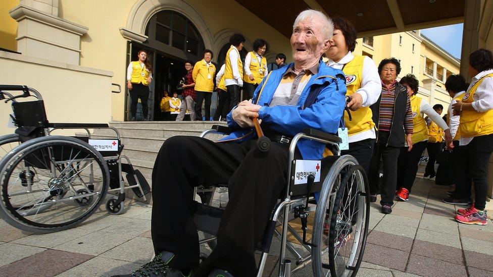 South Korean Suh Byung-gon, 82, is helped by a Red Cross official as he arrives to take part in family reunions with his North Korean family members at a hotel in Sokcho, South Korea (19 October 2015)