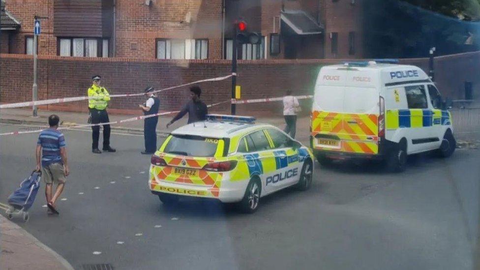 Two police cars in front of police tape and two officers