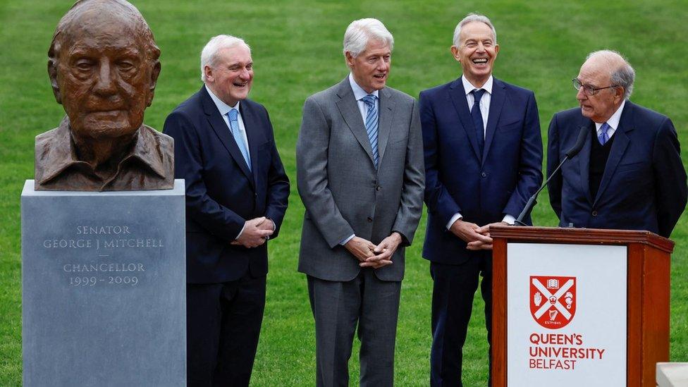 Former Irish Prime Minister (Taoiseach) Bertie Ahern, former US President Bill Clinton and former Britain's Prime Minister Tony Blair react as former US Senator George Mitchell speaks after unveiling of a bust depicting him during an event marking the 25th anniversary of the Good Friday Agreement at Queens University Belfast