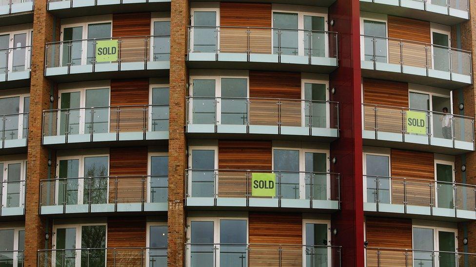 A man looks out of a newbuild apartment block in central London on April 21, 2008 in London, England.