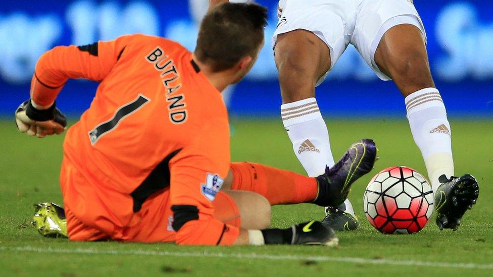 Stoke City's Jack Butland tackles Swansea City's Andre Ayew