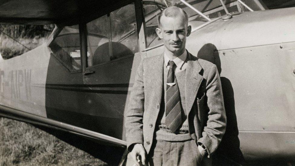 Black and white portrait of Harold Wingham standing next to a plane