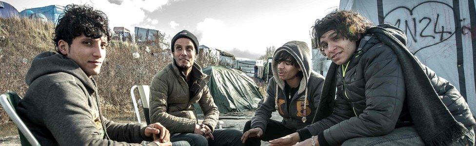 Young men sit around a fire on 19 February 2016 in the Jungle camp of migrants and refugees in Calais, northern France