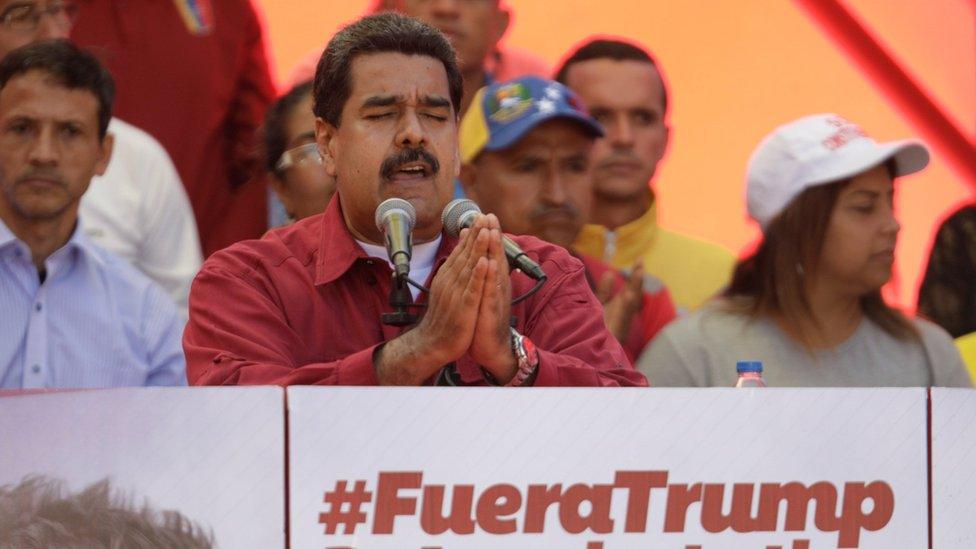 President Nicolás Maduro gives a speech by a sign reading, "Trump go away from Latin America" at a rally against President Donald Trump in Caracas, Venezuela, August 14, 2017