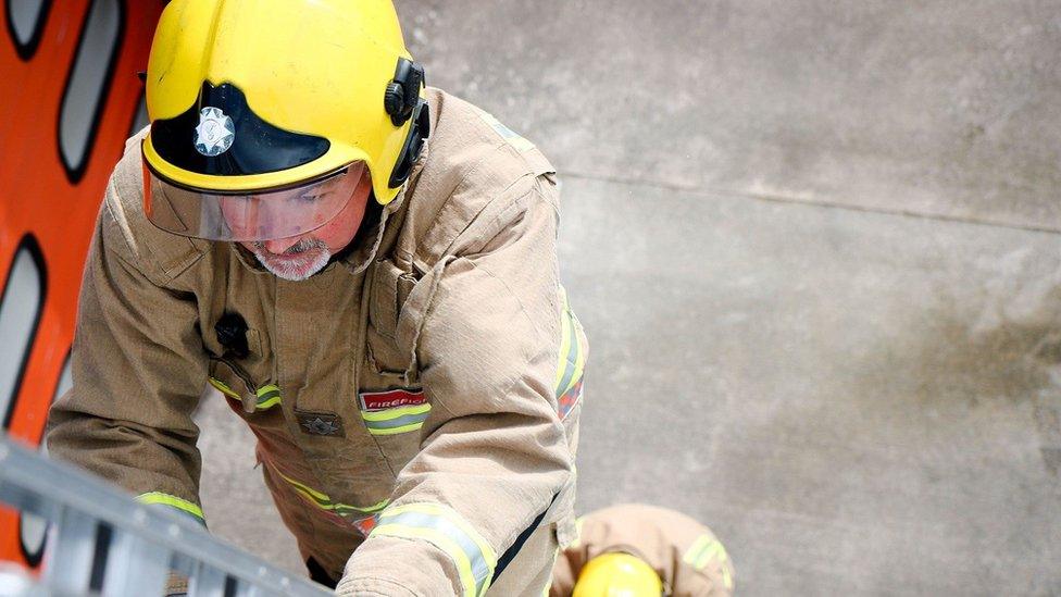 Firefighters climb a ladder