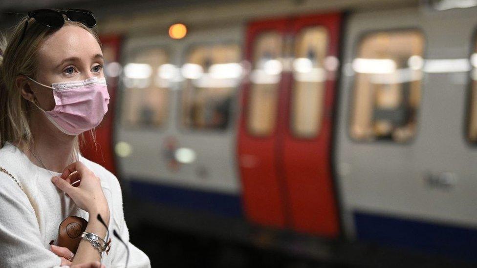 Woman in a mask waiting for a train