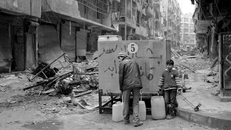 People collect water from a tank in eastern Aleppo