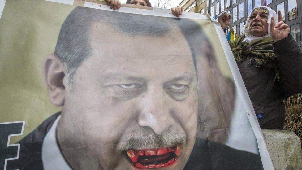 Kurdish people display a picture of Turkish President Tayyip Erdogan during a protest outside an EU-Turkey summit in Brussels