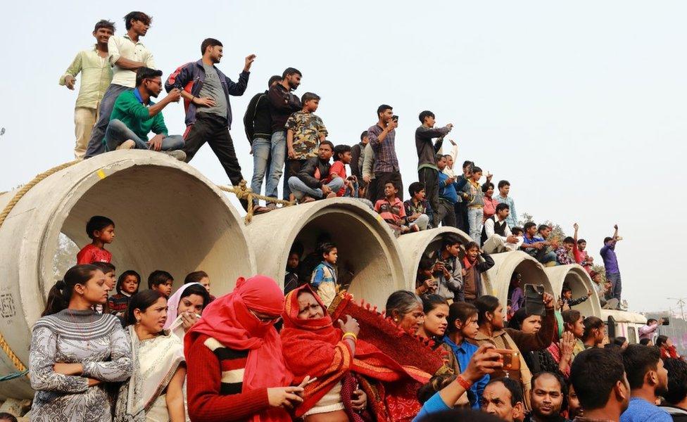 Locals take photos and film videos of the procession.