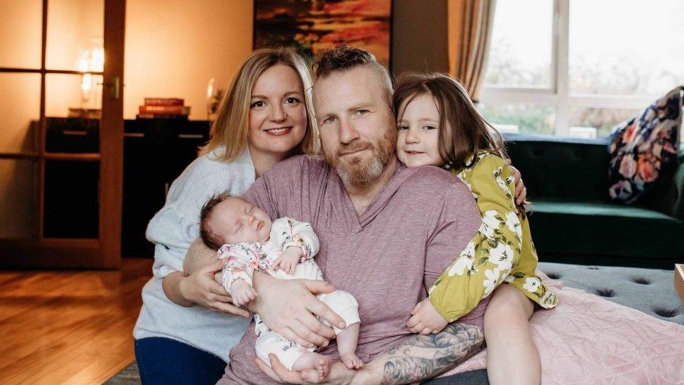 Family portrait photo of a man and woman with a young child and a baby in arms