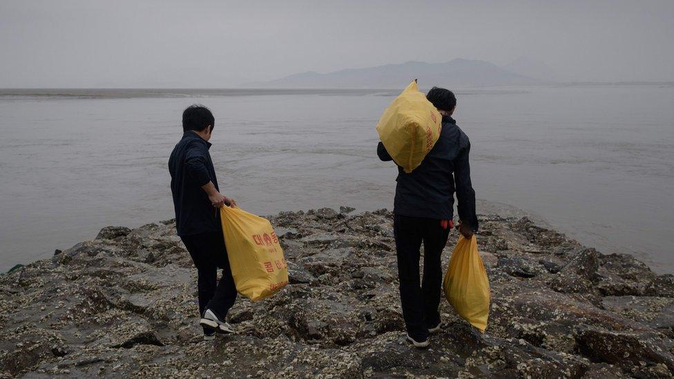 North Korean defector activists carry bags of bottles containing rice, money, and USB sticks, on Ganghwa island, west of Seoul on May 1, 2018.