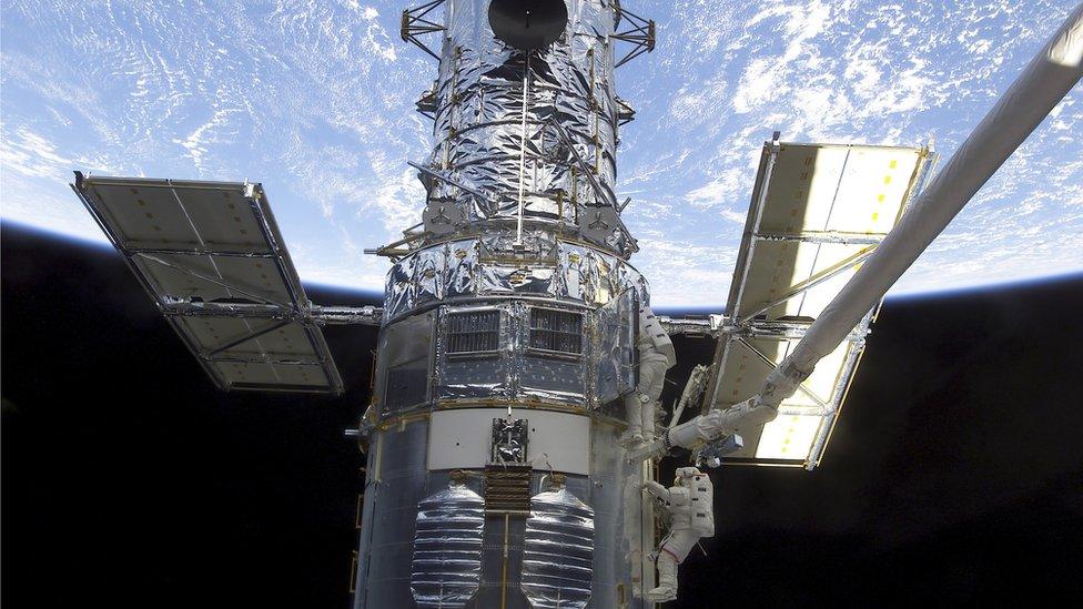 Astronauts participate in extravehicular activity on the Hubble Space Telescope.