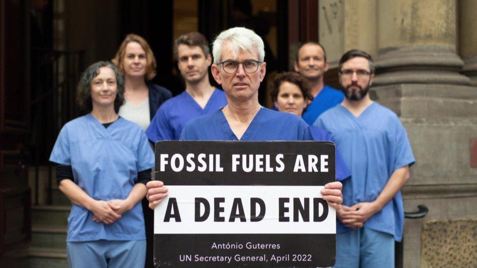 David McKelvey holding a sign saying fossil fuels are a dead end in front of other medical professionals