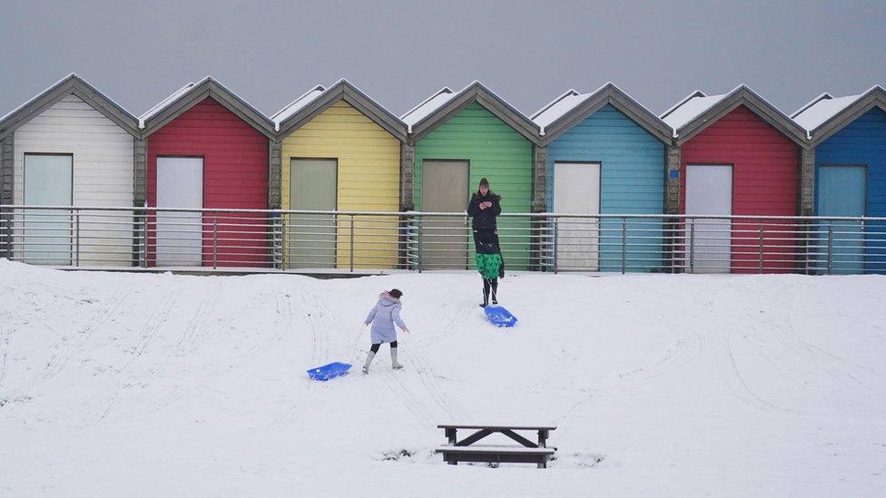 People walk through the snow beside the beach huts at Blyth in Northumberland, as temperatures are tipped to plunge to as low as minus 11C in parts of the UK over the weekend.