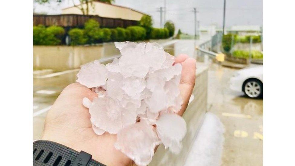 A person holds up a handful of large hailstones in Gympie, Queensland