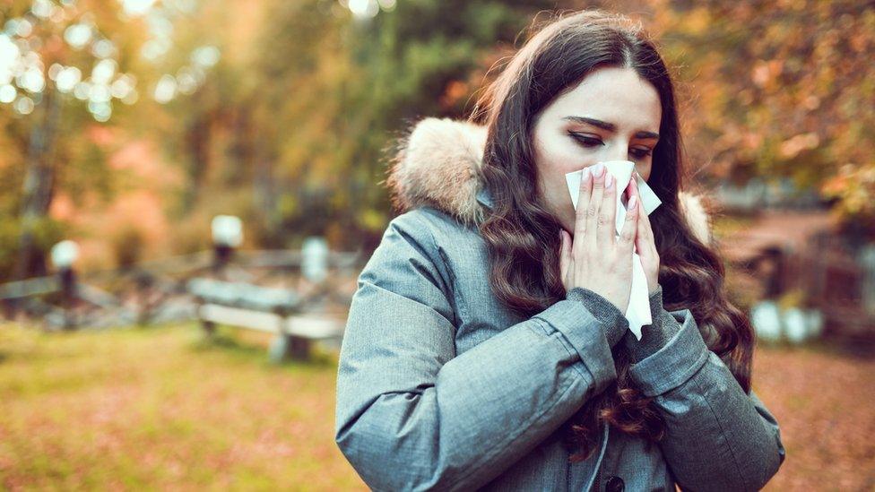 Woman outdoors blowing her nose