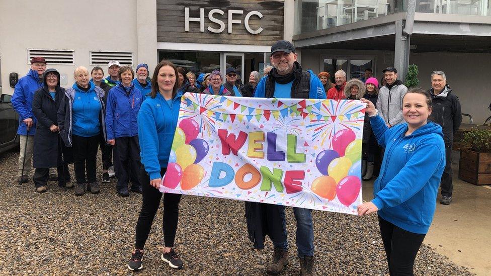 Crowd of people with 'well done' banner