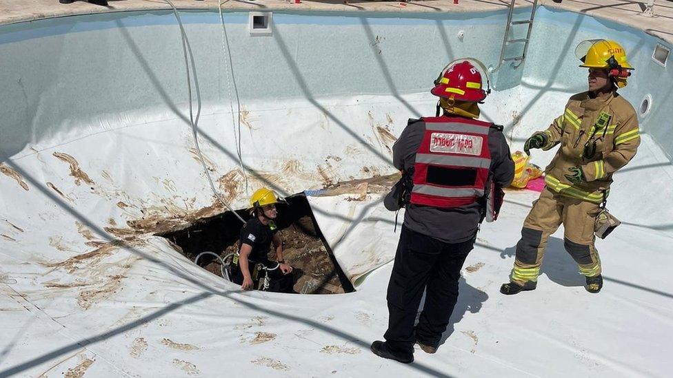 Emergency workers at scene of swimming pool sink hole