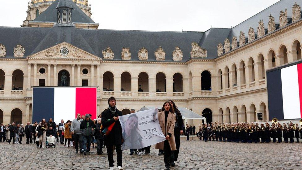 Relatives of the victims leave holding a banner with an image of one of the victims of the 7 October attacks