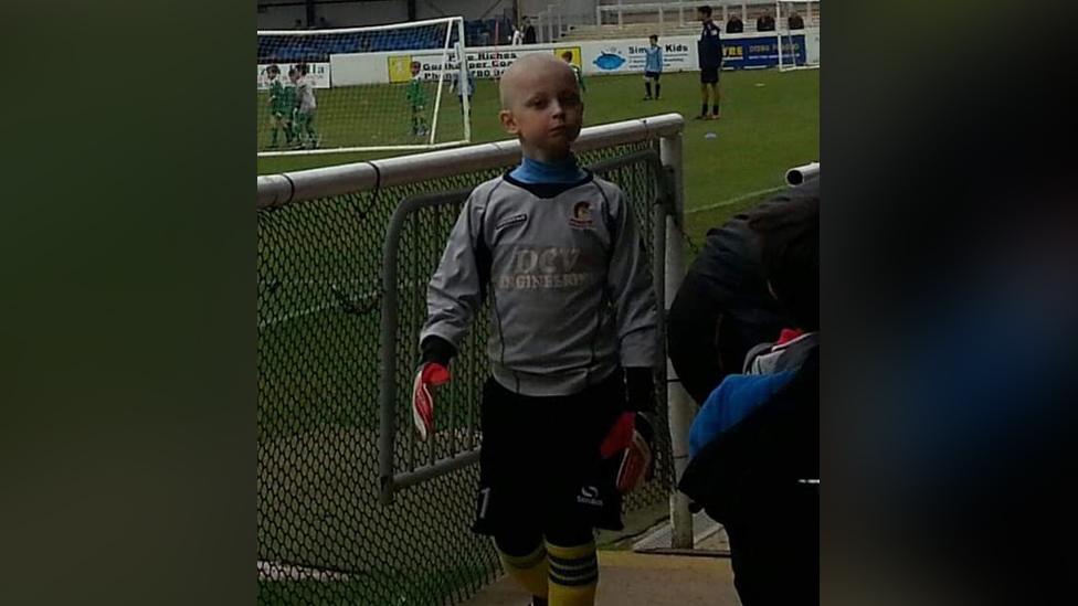 Young Brandon Thacker wearing a goalkeepers kit with a grey long sleeved top and goalkeeping gloves