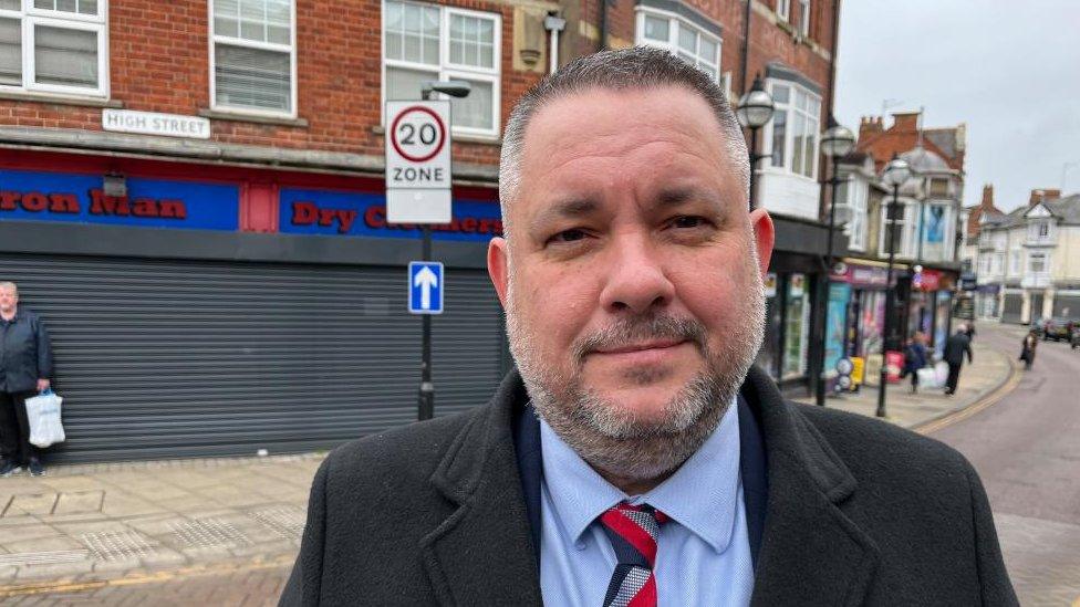 Jason Smithers - man with white beard and wearing a jacket and tie standing in a street