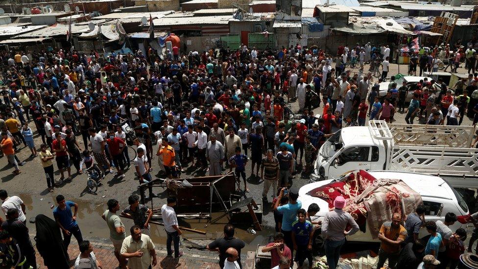 People gather at the scene of a car bomb attack in Baghdad's mainly Shia district of Sadr City