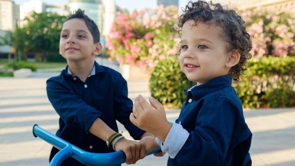 A boy using a walker with his younger brother