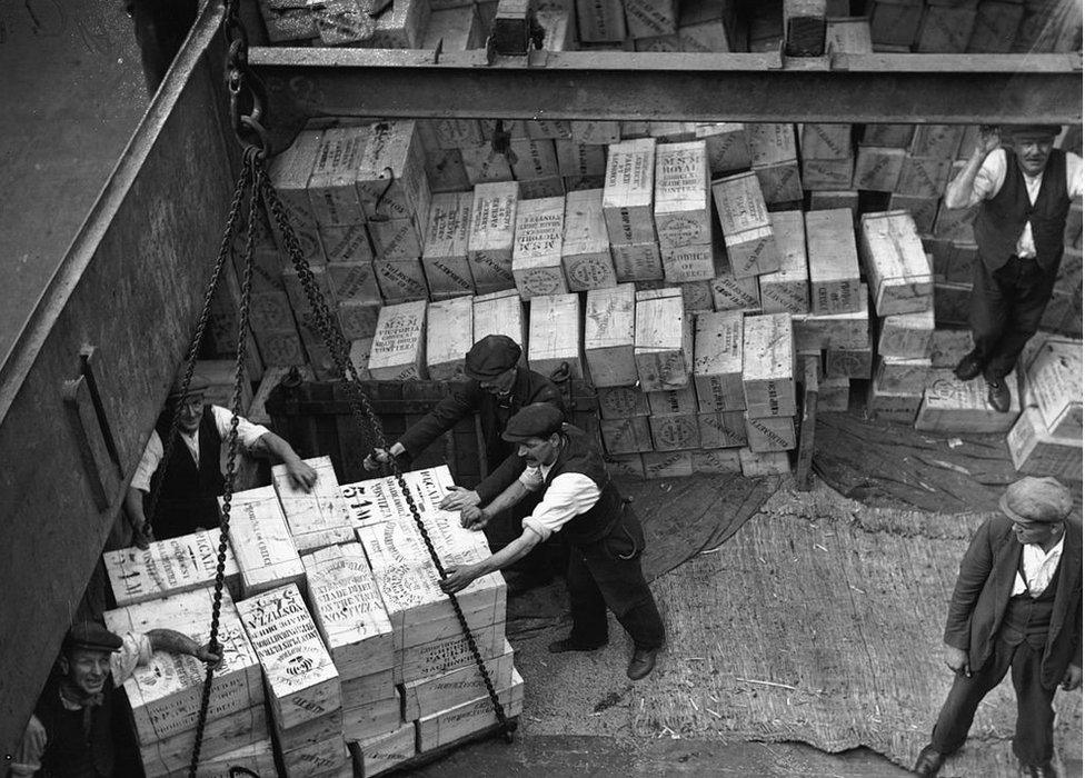 Workmen unloading a consignment of dried fruit from a ship's hold at London Docks in 1930