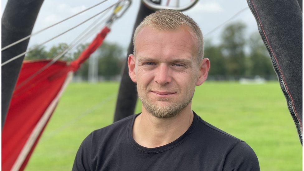 Man in field standing beside a hot air balloon