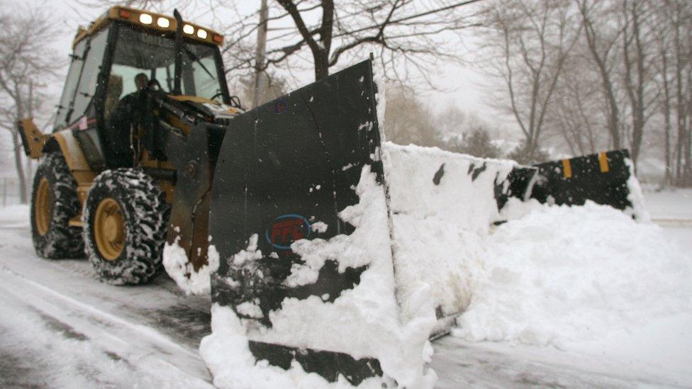 A snow plough clears the road on a winter day