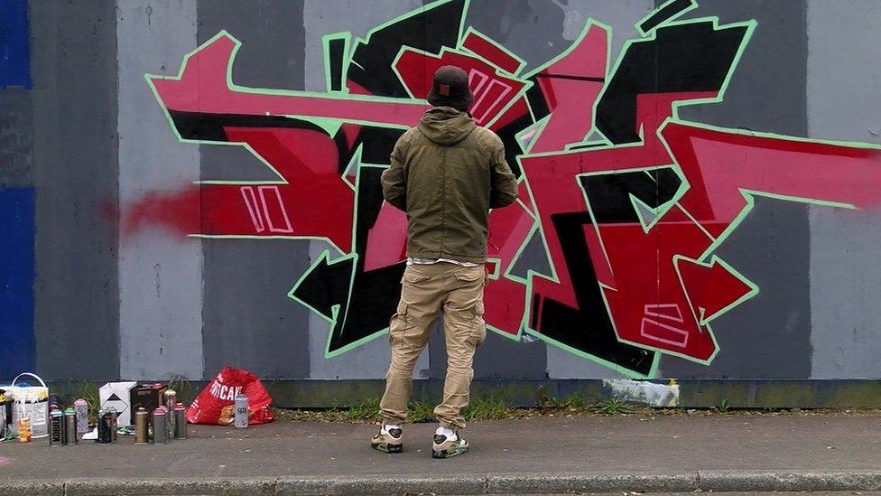 Man stands in front of street art design