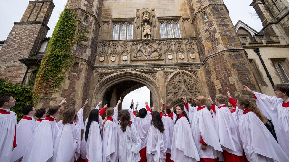 Trinity choir pointing at Henry VIII statue