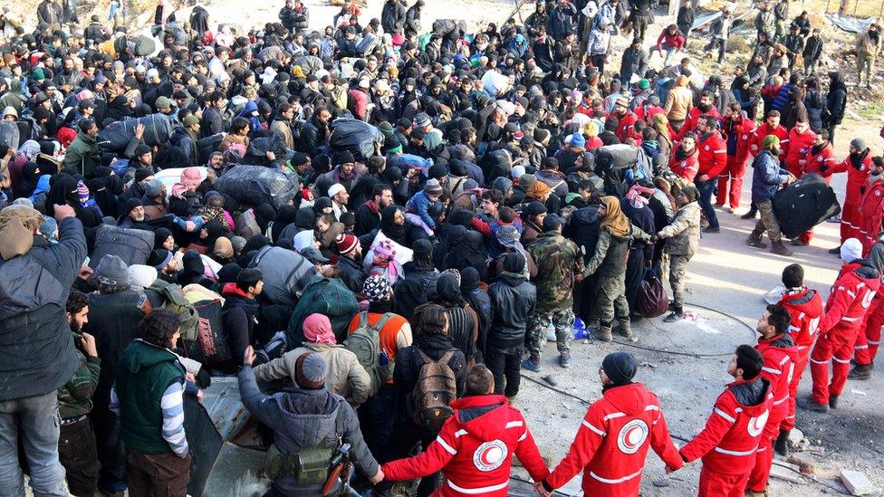 Red Crescent employees hold hands while rebel fighters and civilians wait to be evacuated from eastern Aleppo (18 December 2016)