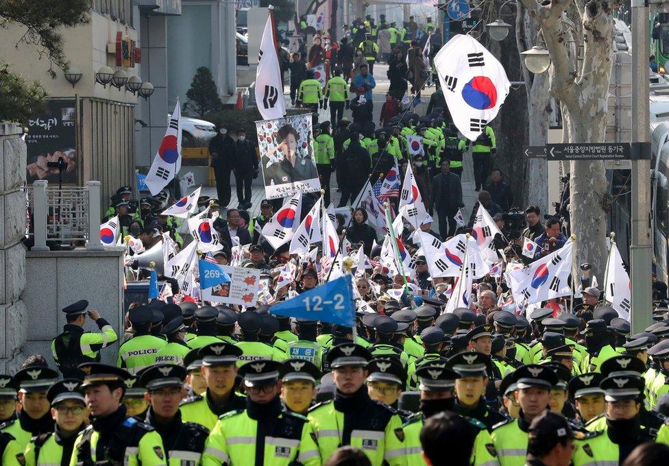 Supporters of South Korean ousted President Park Geun-hye wave national flags and picture of Park outside of a prosecutors' office in Seoul, South Korea, Tuesday, 21 March 2017.