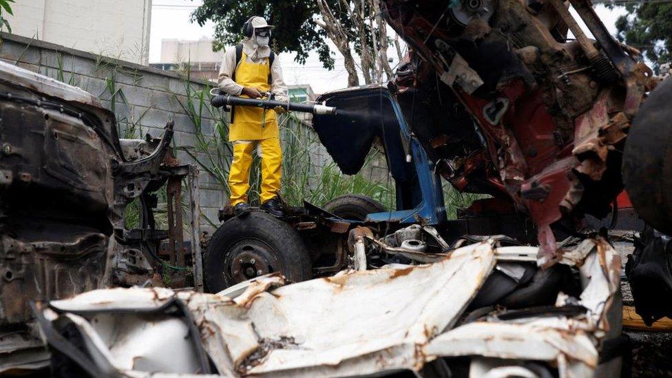 Healthcare agent Robson Ribeiro applies larvicide at a junk yard for vehicles in Sao Paulo, Brazil