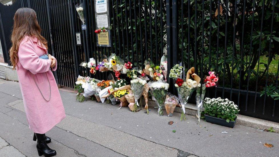 A woman looks at flowers displayed outside the building where a 12-year-old schoolgirl Lola lived and who was murdered on October 18, 2022 in Paris, France