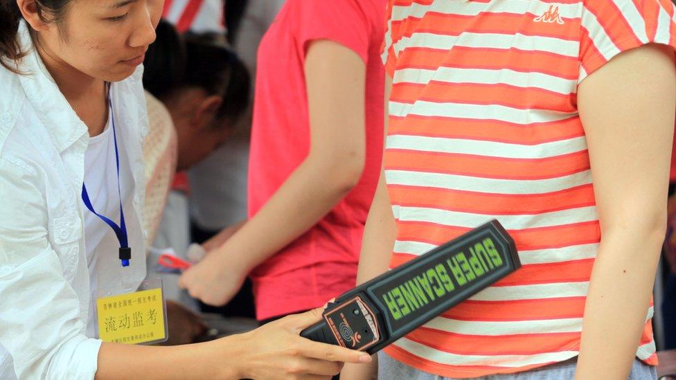 An invigilator (L) checks a student before the 2013 college entrance exam starts in Jilin, northeast China's Jilin province on June 7, 2013.