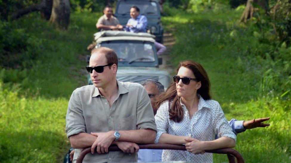 The Duke and Duchess of Cambridge standing up on the back of a jeep