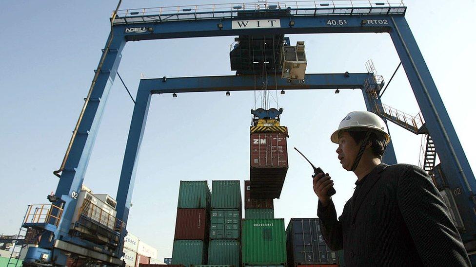 A worker monitors the loading of shipping containers at the container port in Wuhan, in central China