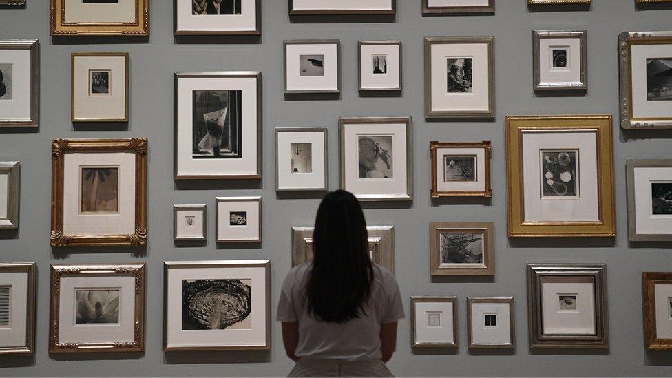 A member of staff poses infront of photographs belonging to Elton John during a press preview for The Radical Eye: Modernist Photography from The Sir Elton John Collection at Tate Modern