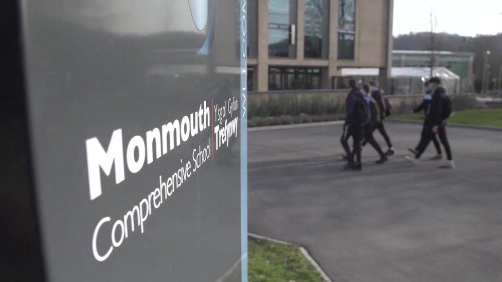 Monmouth Comprehensive school sign, with pupils walking past