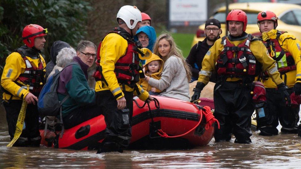 Members of the emergency services evacuate residents from flooded