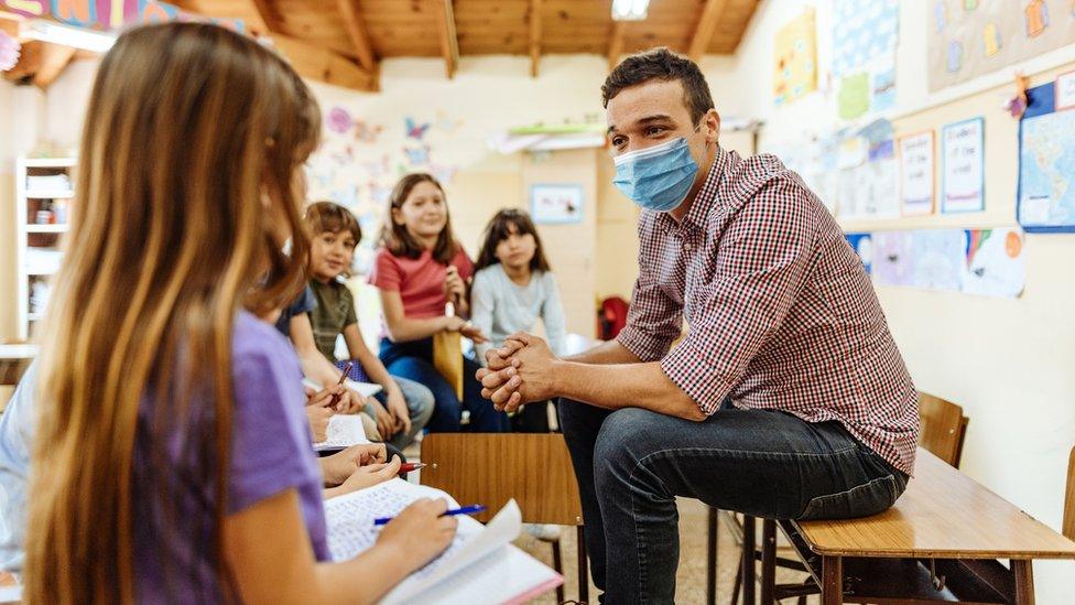 teacher-wearing-mask-sitting-with-pupils.