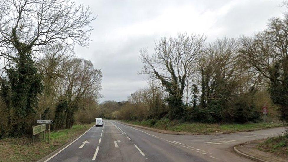 Main road (single carriageway) with right turn marked to "Cornhill" and trees on either side