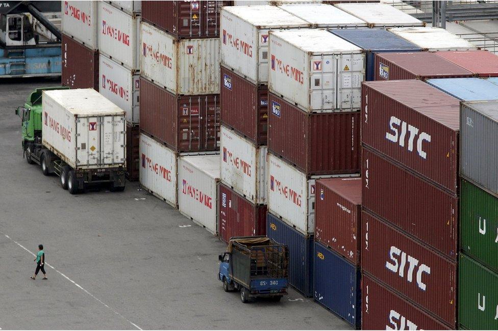 A person walks near containers at Keelung port, northern Taiwan, 30 October 2015