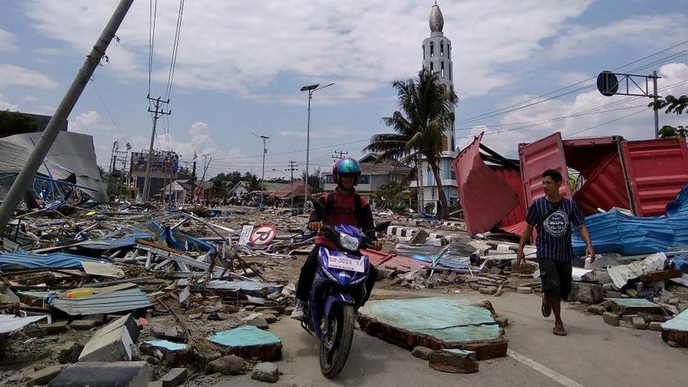 Residents make their way along a street full of debris after an earthquake and tsunami hit Palu, Indonesia. Photo: 29 September 2018